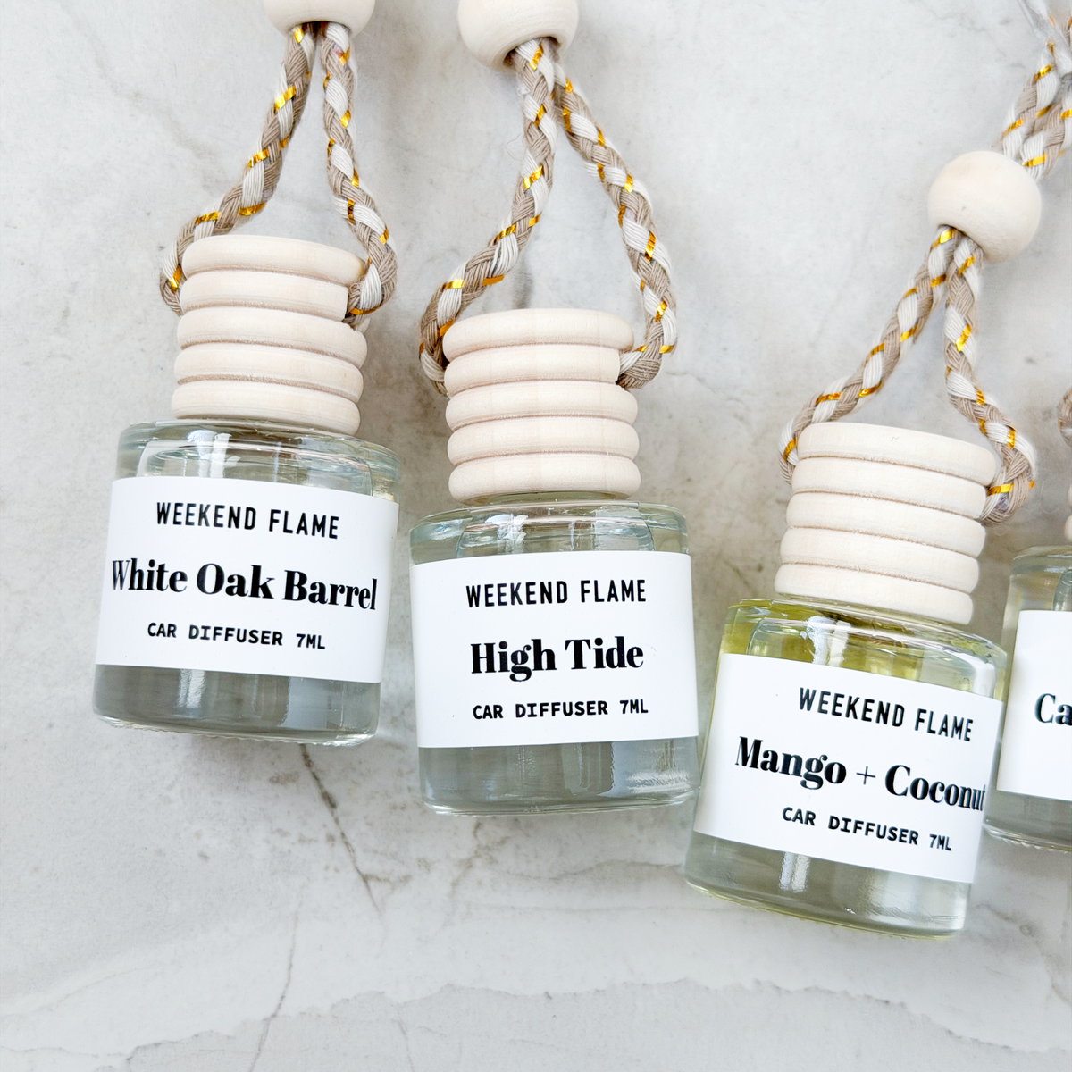 Assorted hanging car diffuser air fresheners displayed on a stone background in multiple fragrance options.