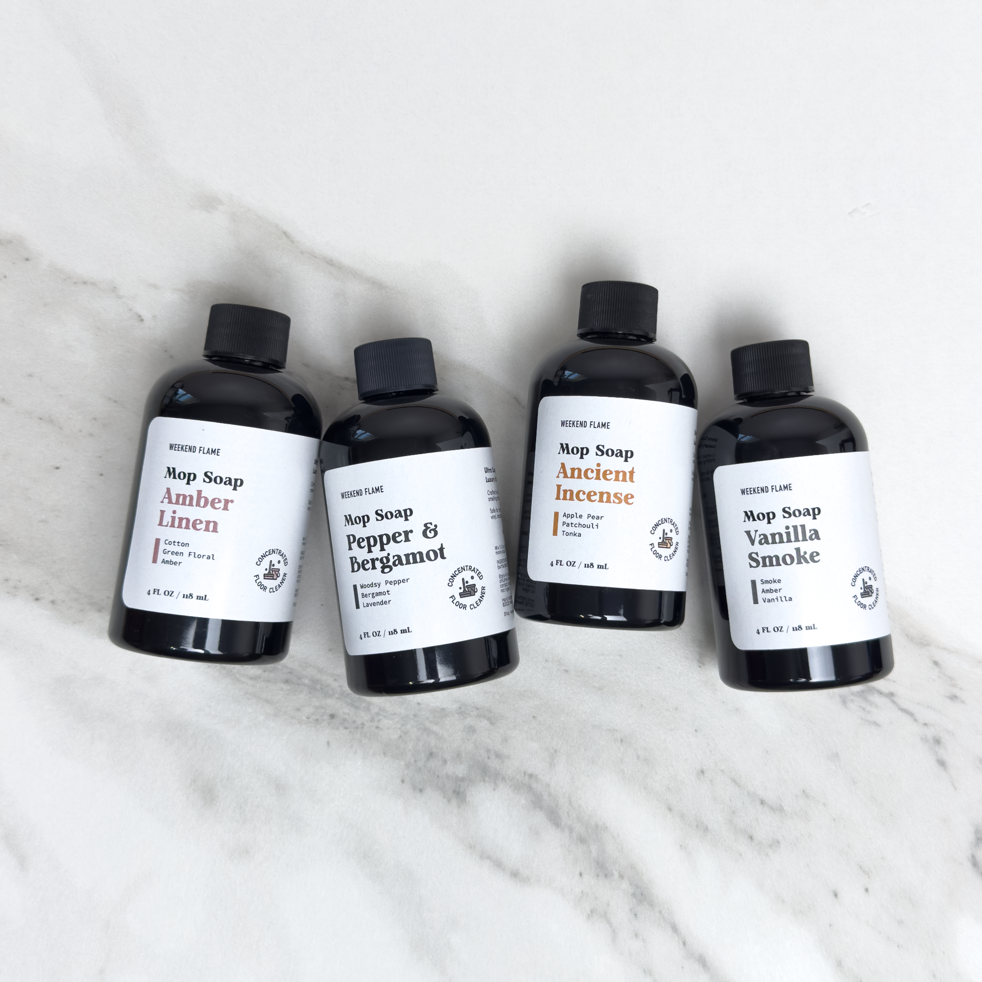 Four sample size bottles of soap with labels on a white marble surface
