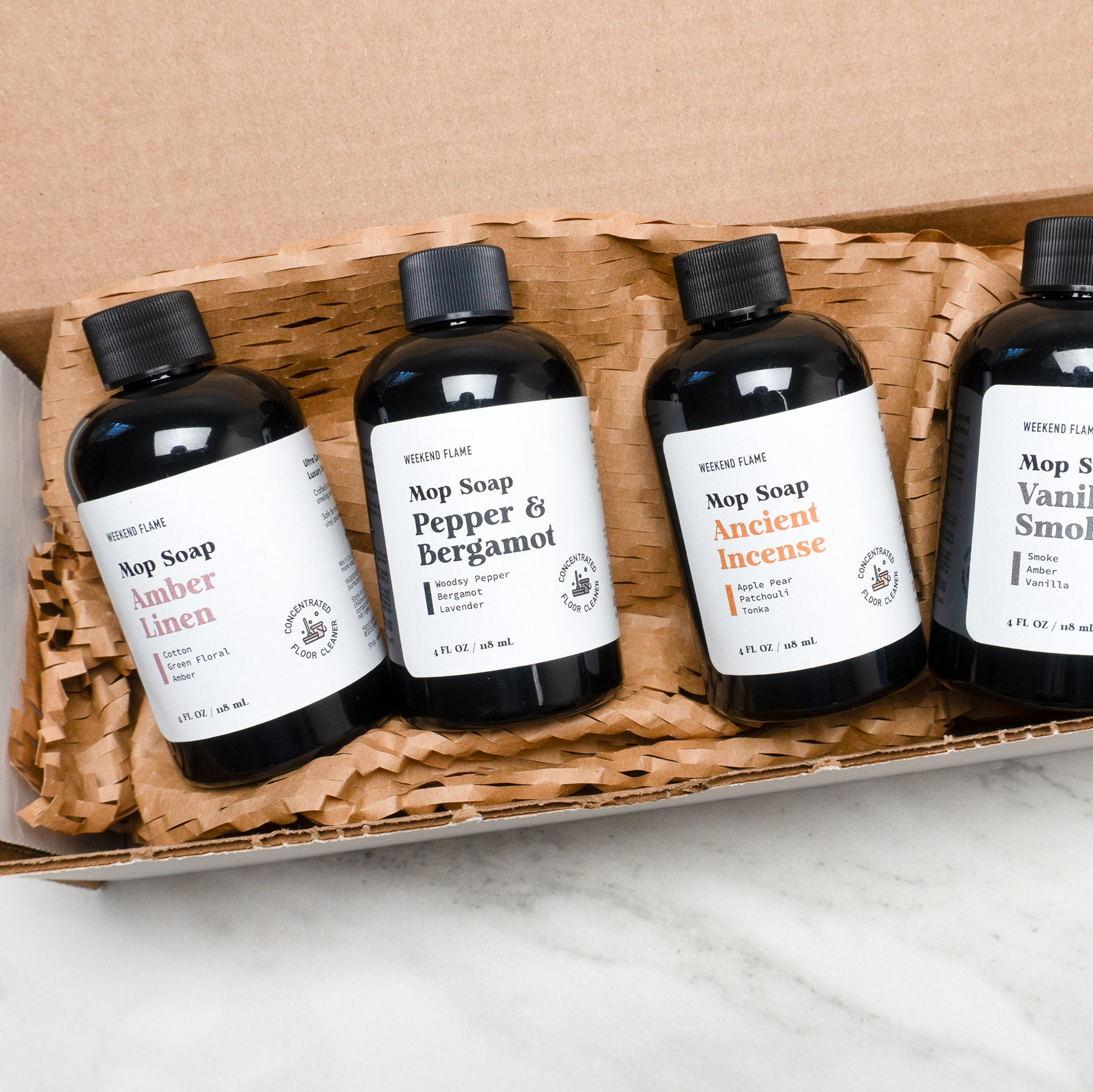 Four bottles of Mop Soap floor cleaner in a cardboard box on a marble surface