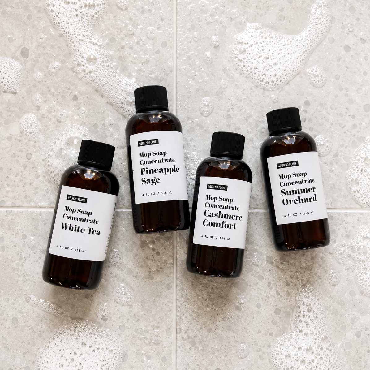 Fresh Retreat Collection: Fresh Retreat trial size Mop Soap sample set featuring White Tea, Pineapple Sage, Cashmere Comfort and Summer Orchard displayed on a lightly soapy tile floor.