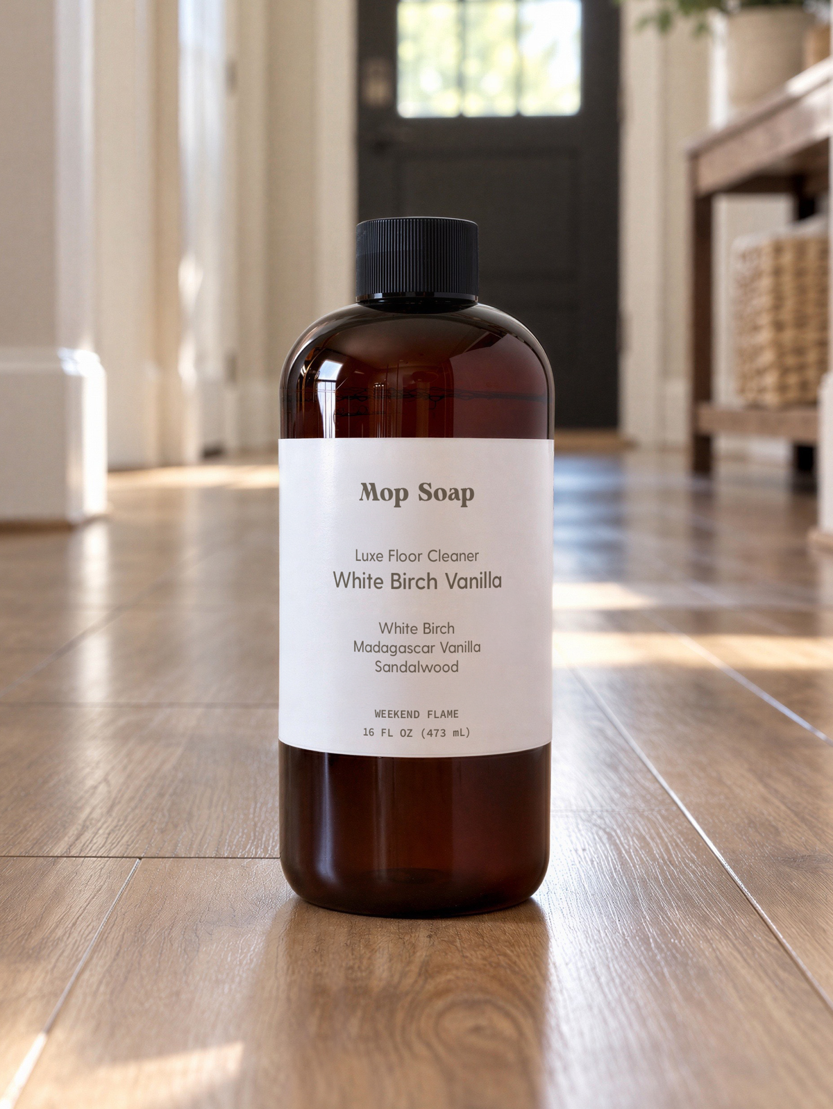 An amber bottle of Mop Soap with a white label, standing on a hardwood floor in a entryway.