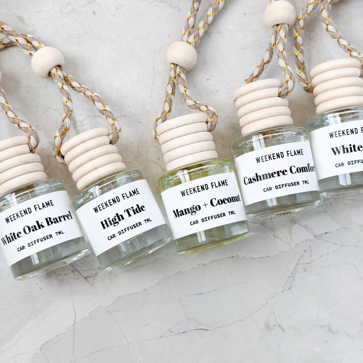 Car fragrance diffusers in assorted scents arranged on a neutral stone background