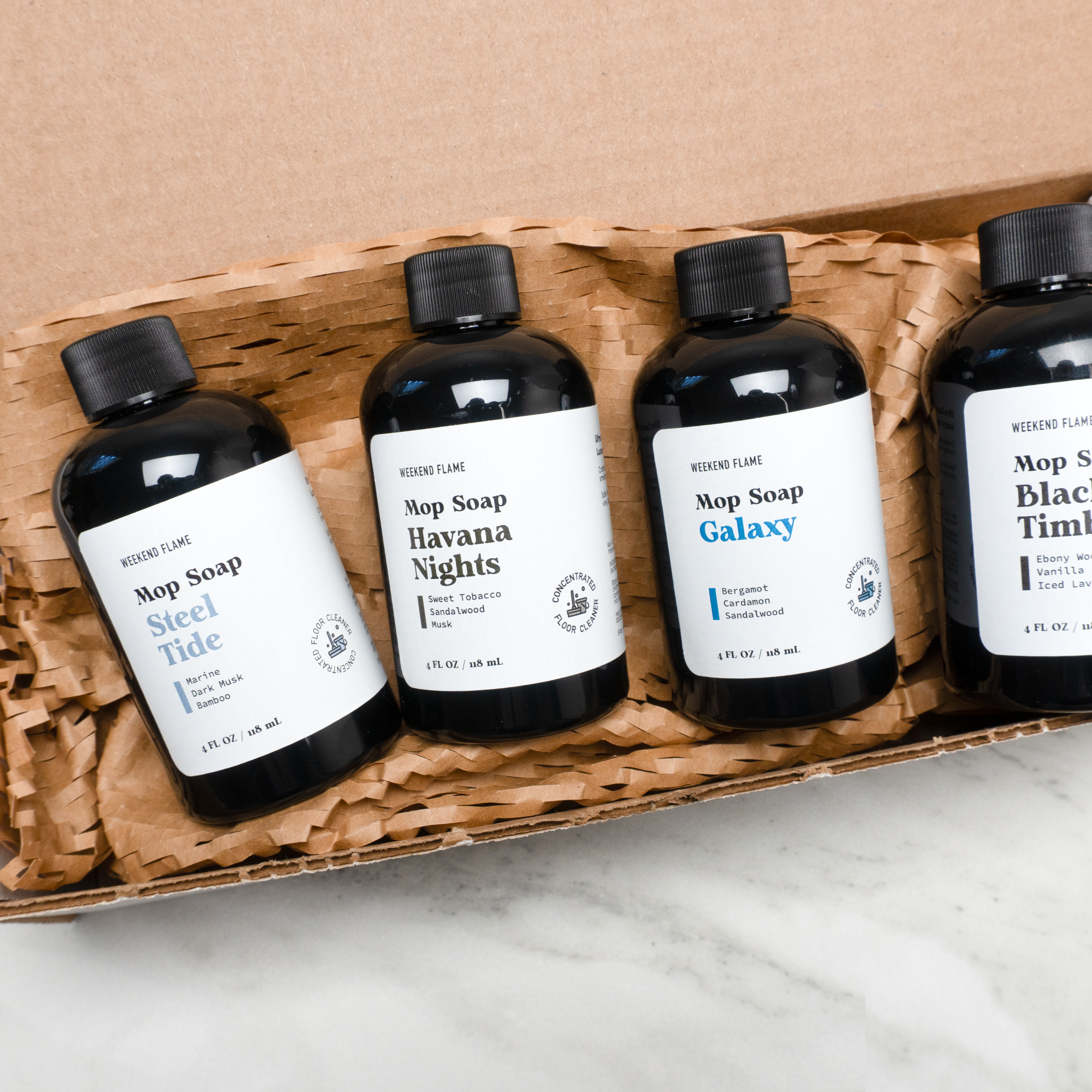 Four bottles of Mop Soap in a cardboard box on a marble surface