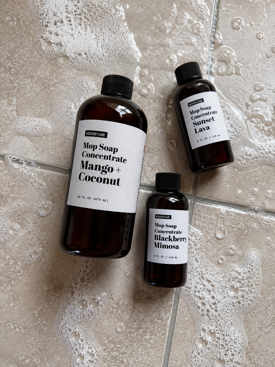 Weekend Flame Mop Soap Concentrate in Blackberry Mimosa and Mango + Coconut with Sunset Lava Multi Surface Cleaner on a freshly cleaned kitchen floor.