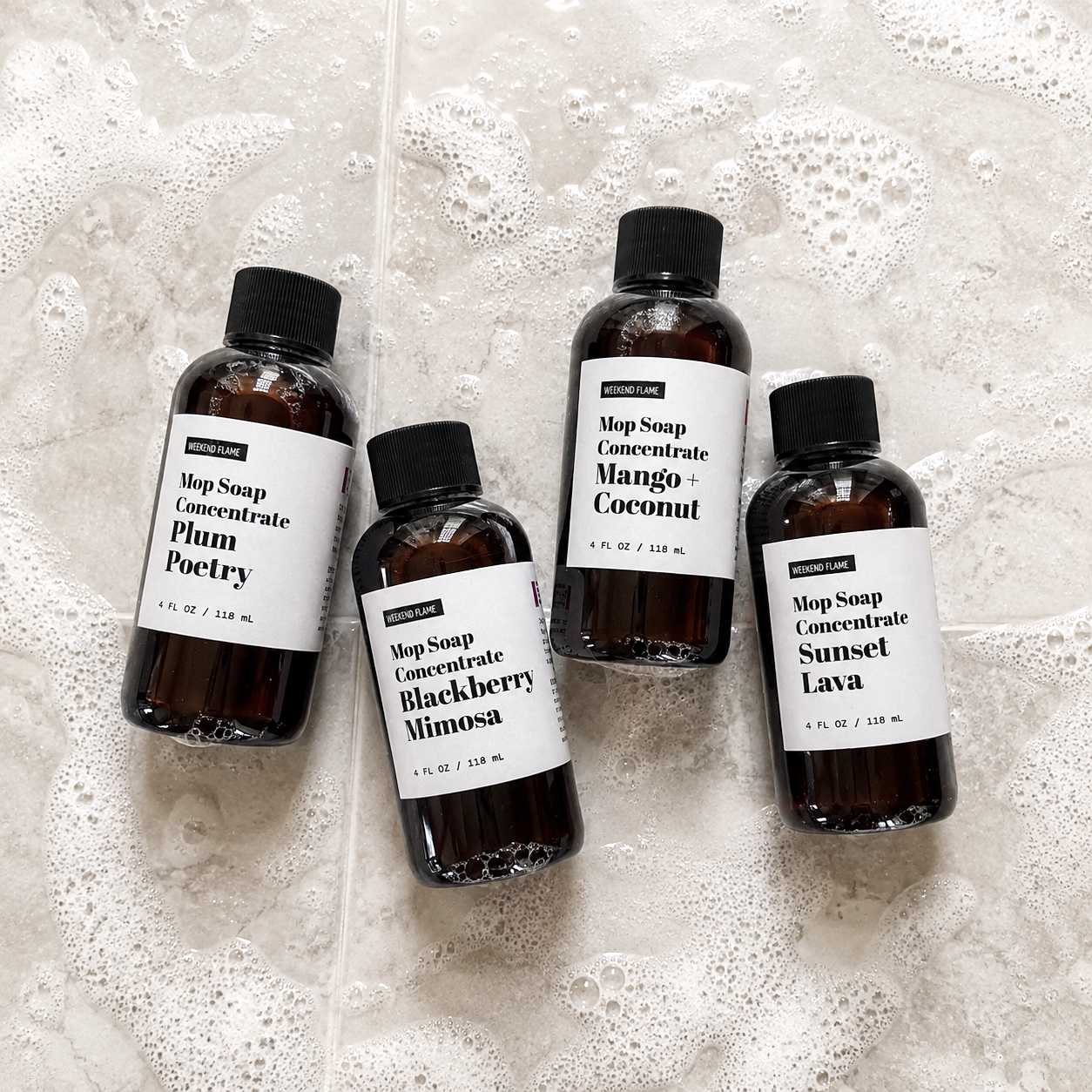 Juicy Escape Collection: Juicy Escape trial size Mop Soap sample set featuring Plum Poetry, Blackberry Mimosa, Mango Coconut and Sunset Lava displayed on a lightly soapy tile floor.