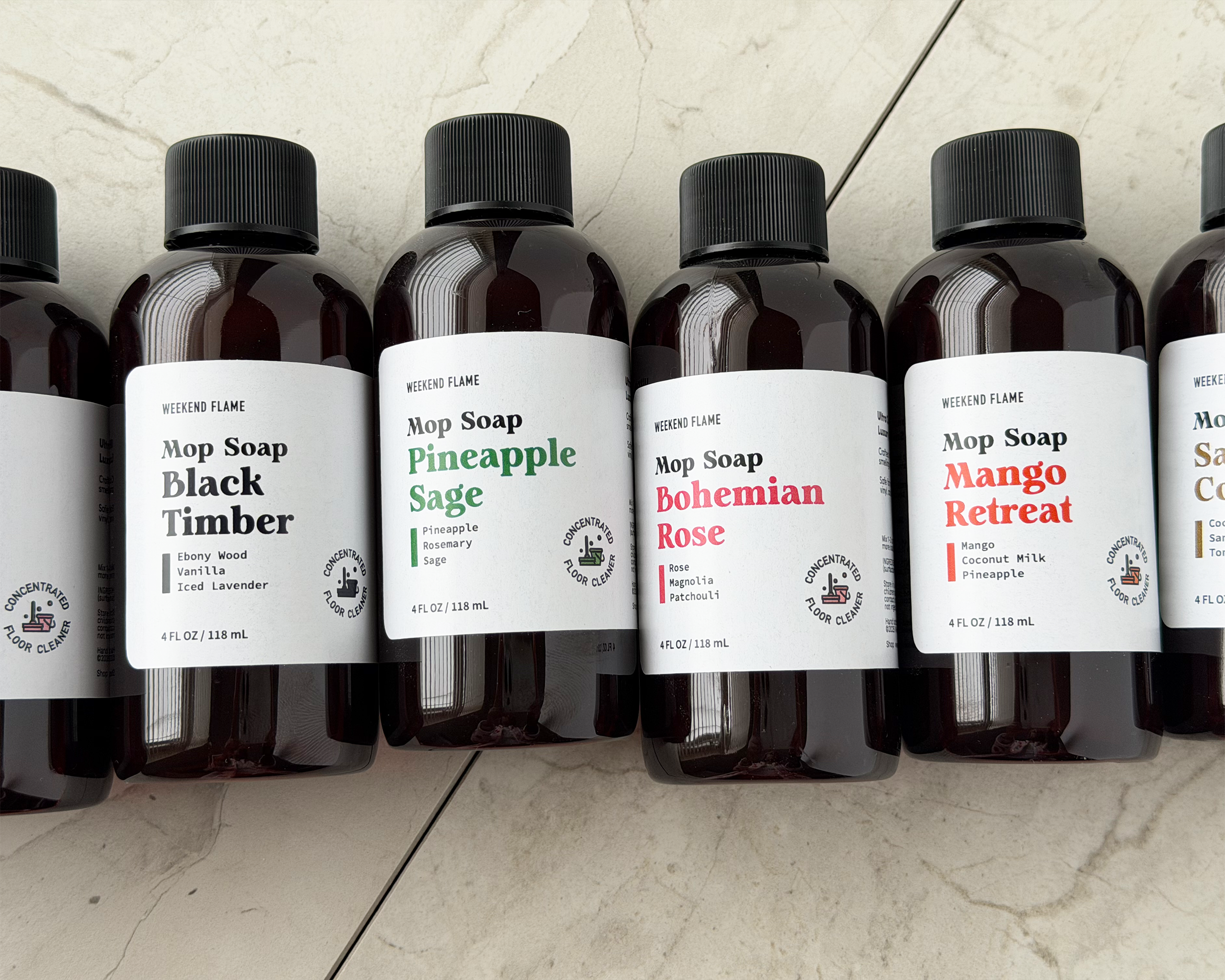 Row of assorted mini Mop Soap bottles with labeled scents on a light background